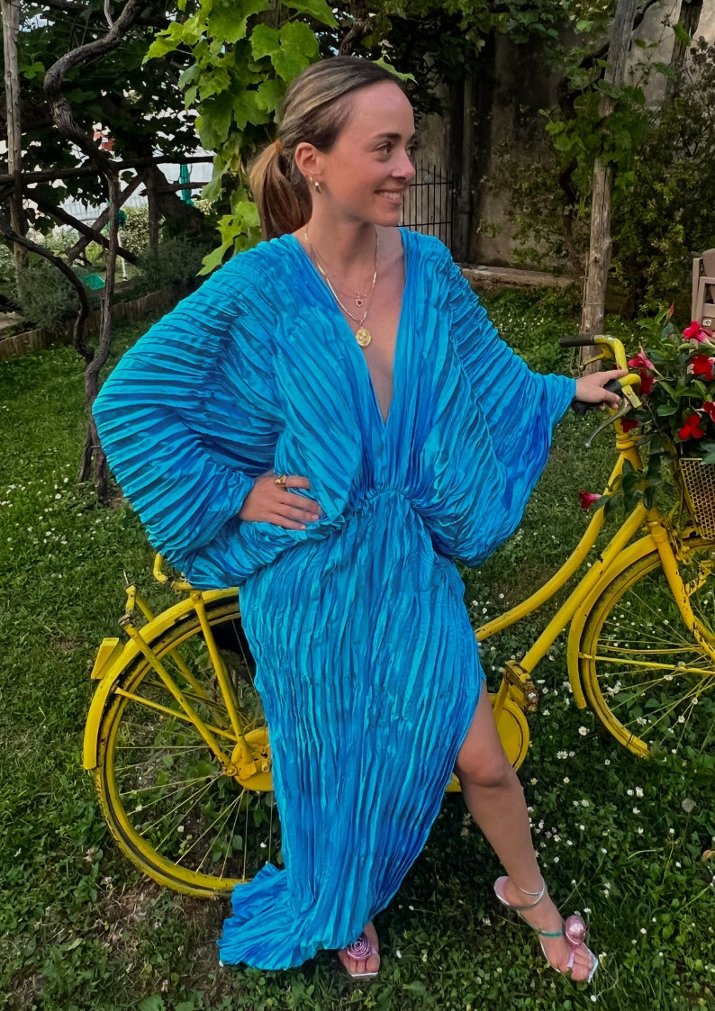 woman standing in her grassy backyard. she is wearing a sparkly brown evening dress, natural makeup and curled hair. she is posing with one arm down and the other on her head.